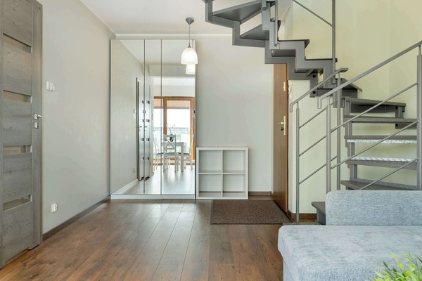 The bright interior with glass balcony doors and stairs leading to the upstairs bedroom blends functionality with style.