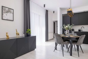 A modern dining area with a black dining table, grey chairs, and a black cabinet with decorative items.