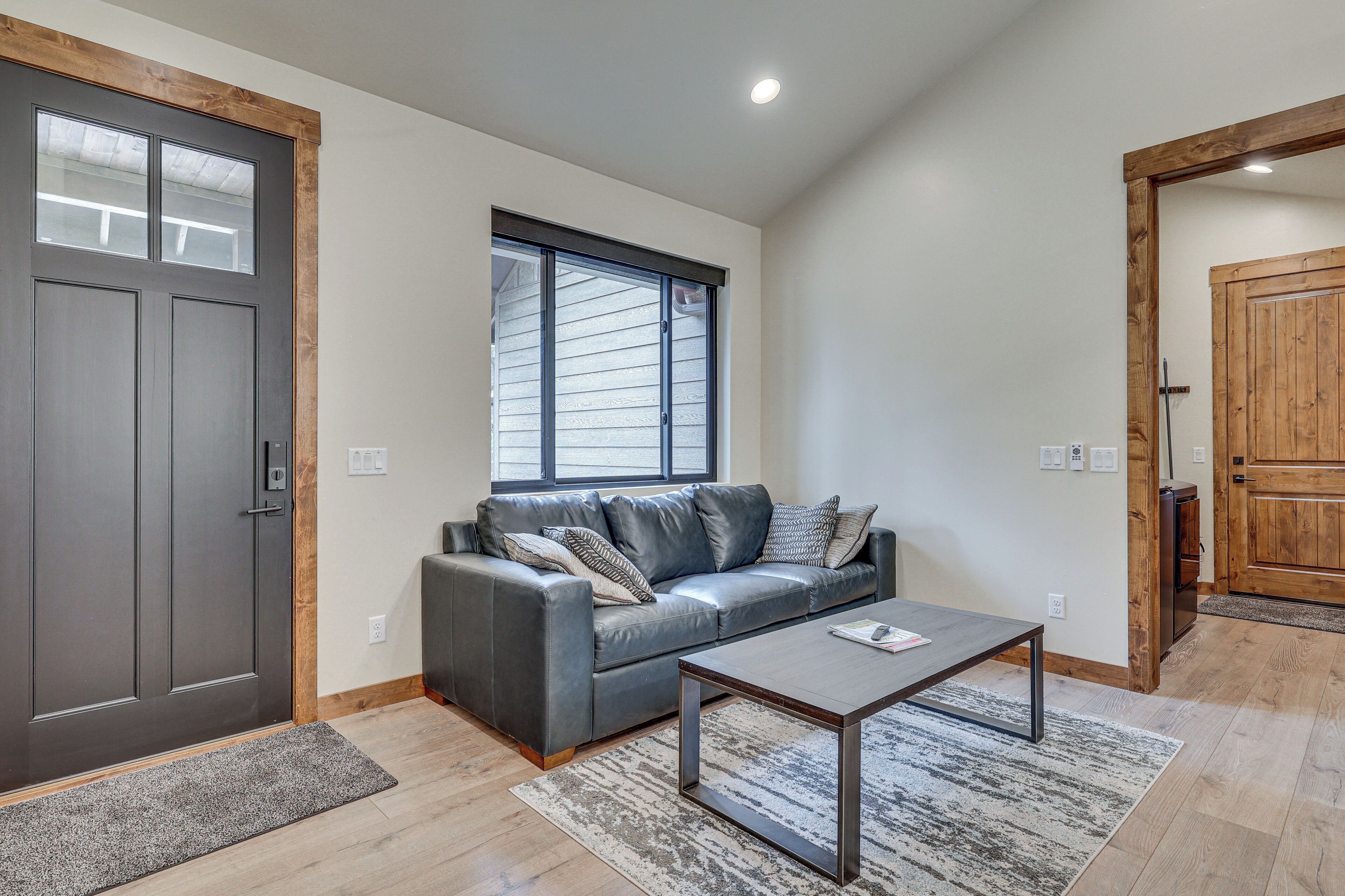 Un salon avec un canapé gris, une table basse et une porte en bois.