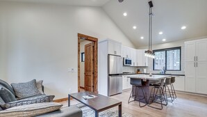Cocina moderna con armarios blancos, electrodomésticos de acero inoxidable y una isla grande con taburetes de bar.