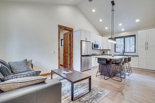 A modern kitchen with white cabinets, stainless steel appliances, and a large island with bar stools. - Contemporary & Cozy! Pinetop Country Club Casita (Pinetop)