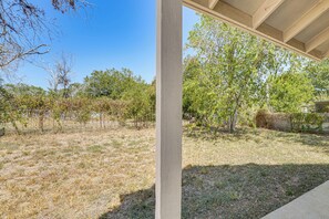 A covered outdoor area with a view of a dry grassy field and trees.