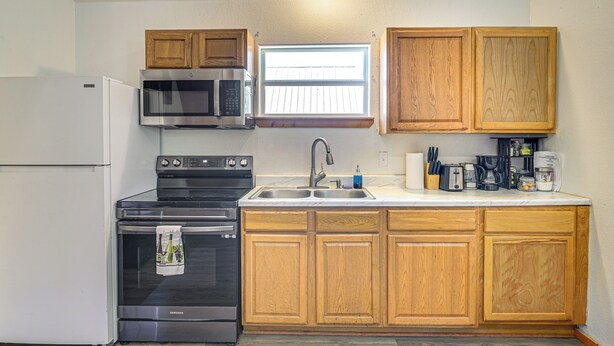 Una cocina compacta con refrigerador, estufa, microondas y gabinetes de madera.