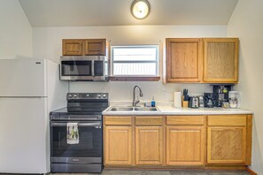 A compact kitchen with a refrigerator, stove, microwave, and wooden cabinets.