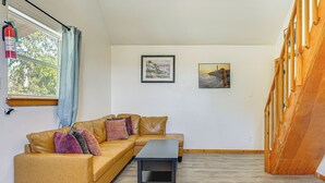 Una habitación con un sofá de cuero marrón, una mesita y dos cuadros en la pared.
