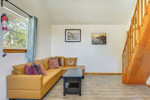 A room with a brown leather sofa, a small table, and two framed pictures on the wall.