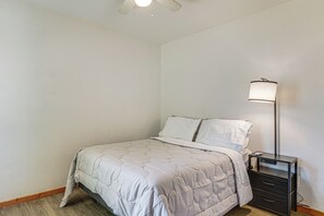 Een slaapkamer met een bed, nachtkastje, lamp en een wandradiator.