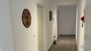 Un couloir décoré d’une tête de cerf en bois, avec une porte, un tableau encadré et un téléphone fixé au mur.