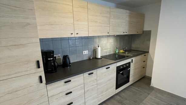 Une cuisine moderne avec des meubles en bois clair, un plan de travail noir et un lave-vaisselle encastré.