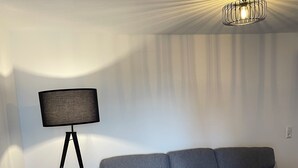 Un salon moderne avec un canapé gris, une lampe sur pied et une table ronde.