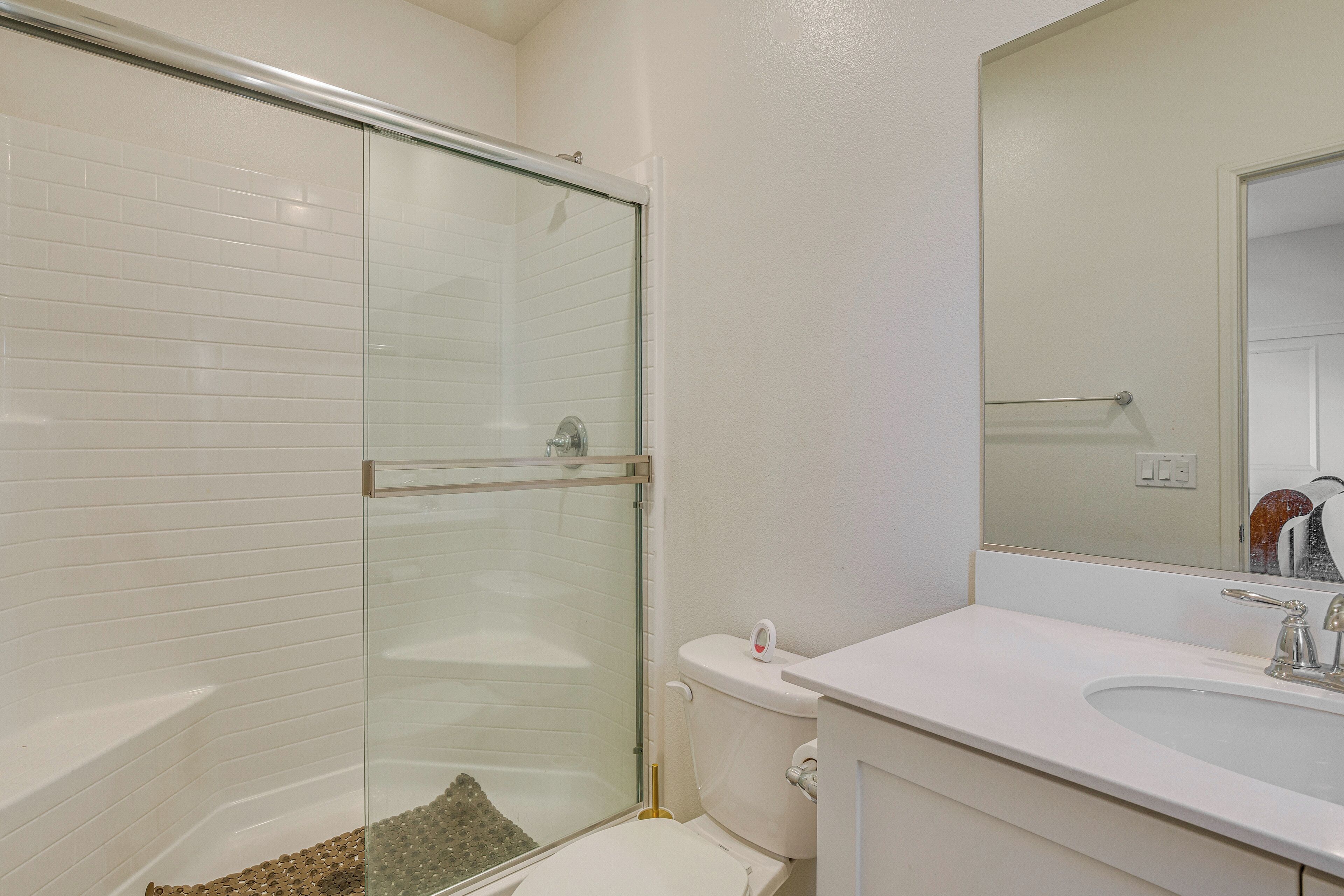 A bathroom with a glass-enclosed shower, a white sink, and a mirror above the sink.