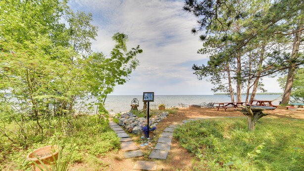 A stone pathway leading to a beach area with picnic tables and a signpost. - Private Beach! Year-round Lake Superior Retreat (Big Bay)