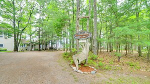 A rustic wooden sign with the text "Tranquility Haven" surrounded by a natural stone border, set in a forested area with a gravel path leading to a house. - Private Beach! Year-round Lake Superior Retreat (Big Bay)