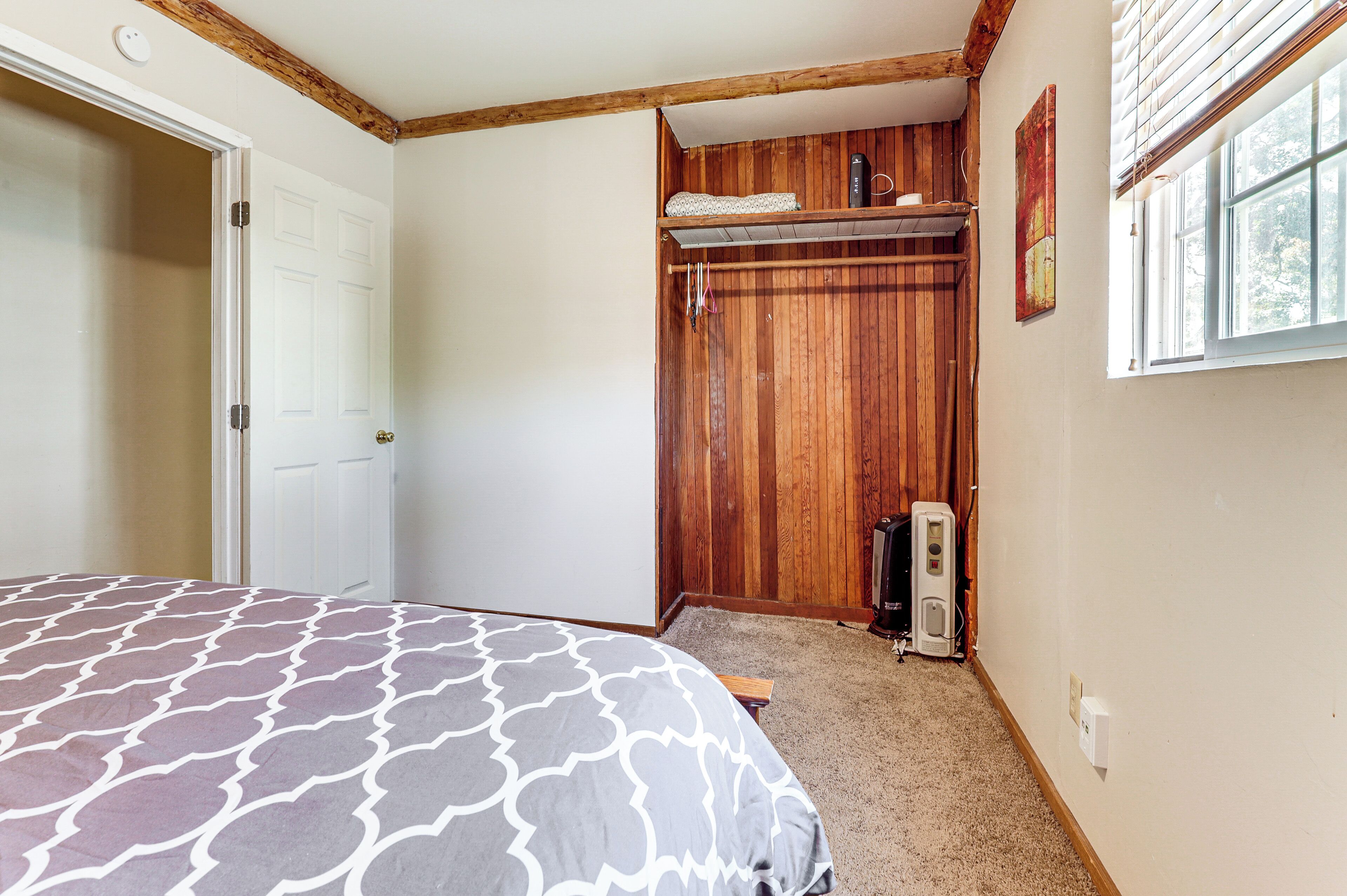 Un dormitorio con una cama, un armario de madera y una ventana.