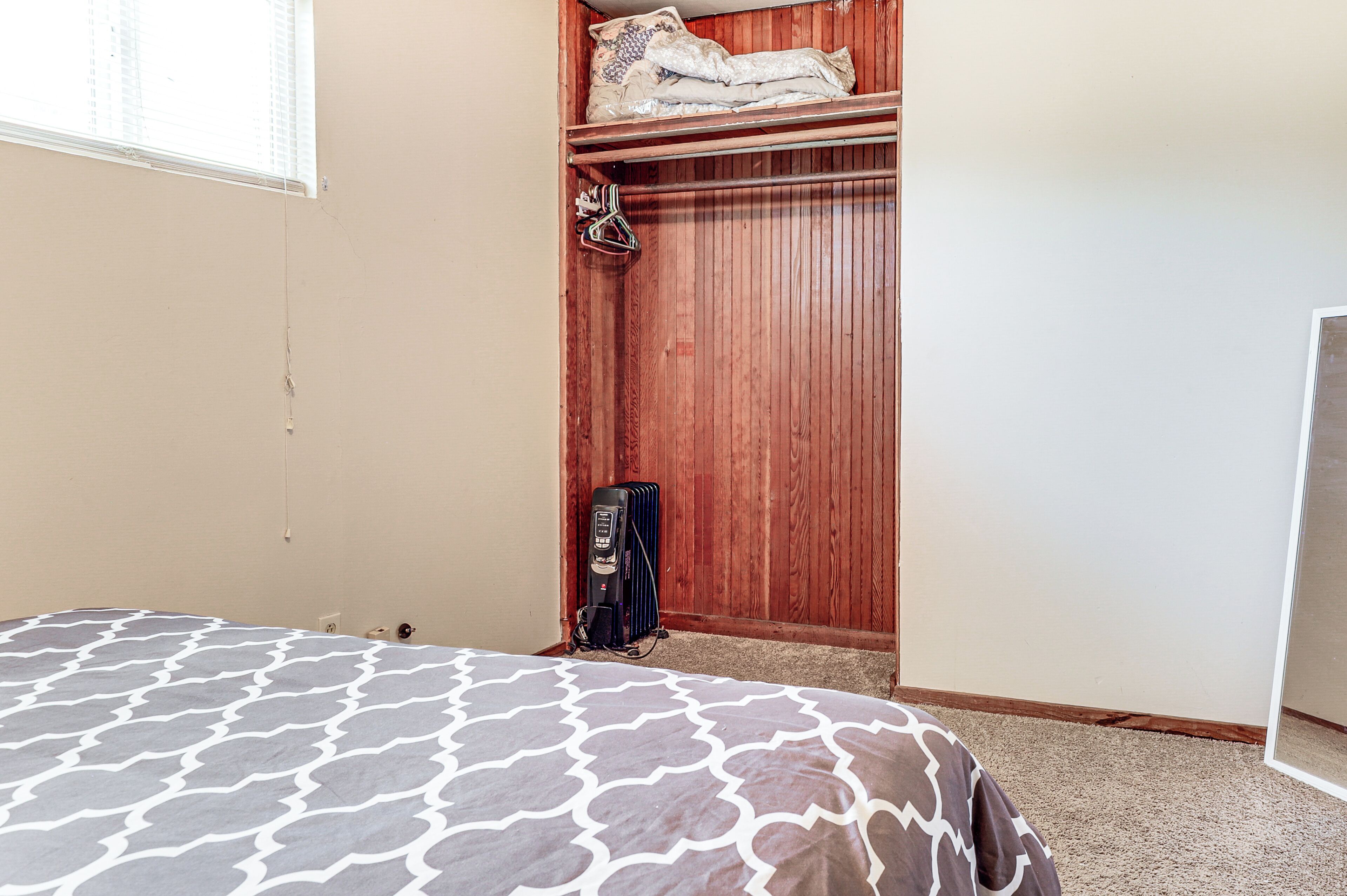 A bedroom with a bed, a wooden closet, and a radiator.
