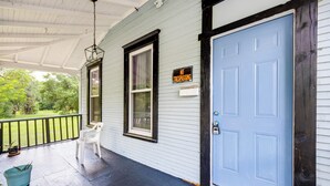 A porch with a blue door, a 'NO TRESPASSING' sign, and a welcome mat.