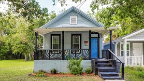A two-story house with a blue door, a front porch, and a small garden.