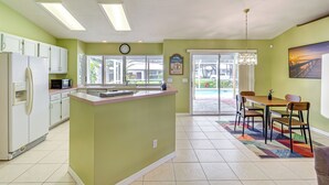 A kitchen with a central island, white cabinets, a microwave, and a refrigerator. - 7 Mi to River & Ocean: Family Getaway in Sebastian (Sebastian)