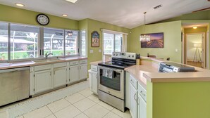 A kitchen with a dishwasher, oven, and a clock on the wall. - 7 Mi to River & Ocean: Family Getaway in Sebastian (Sebastian)