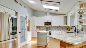 Una cocina moderna con armarios blancos, una isla grande con encimera de mármol y horno empotrado.