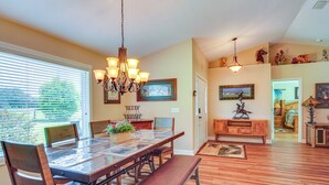 A dining area with a wooden table, chairs, and a bench. There is a chandelier above the table and a window with blinds. - Welcoming Home w/ Yard on 20 Acres in High Springs (High Springs)
