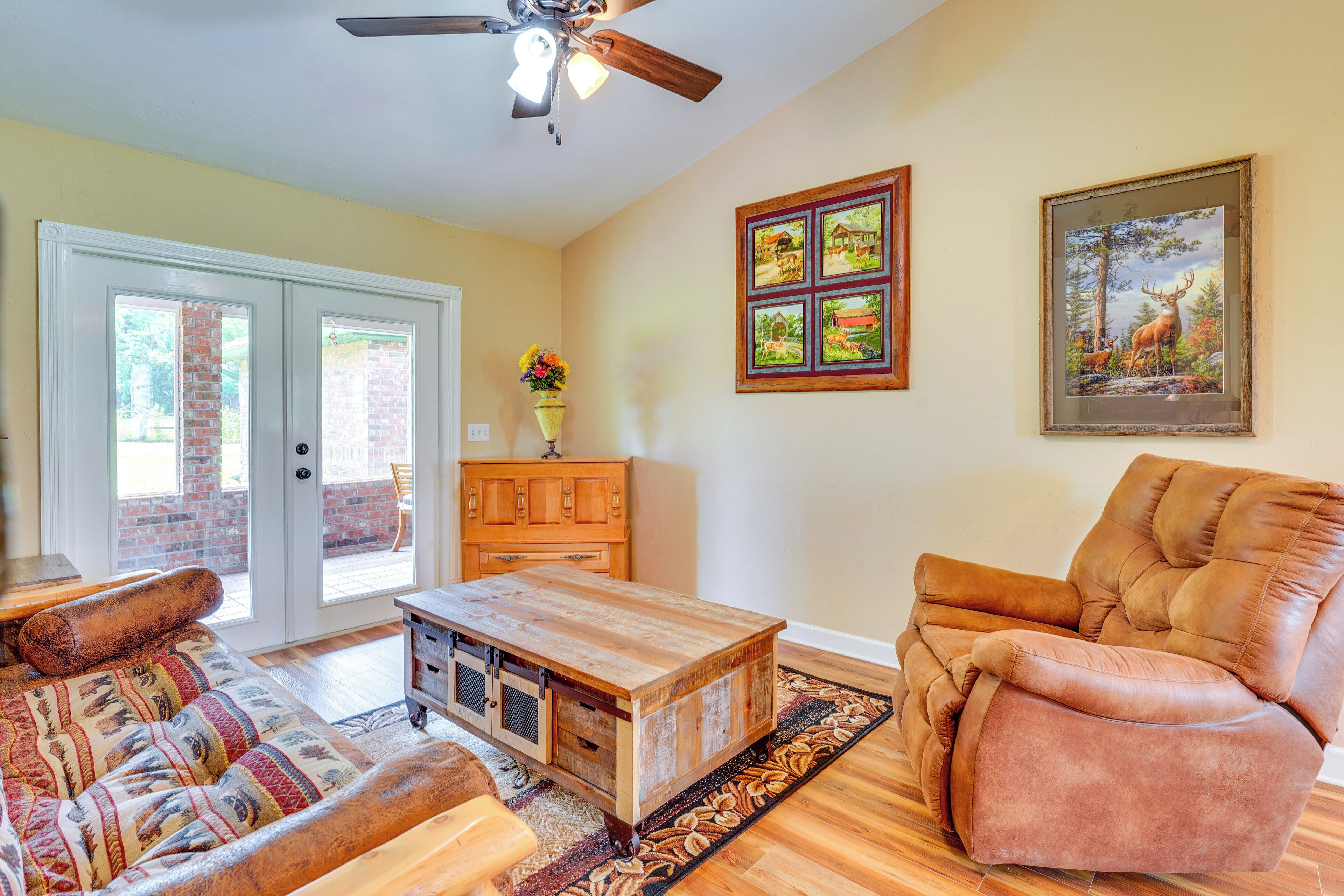 A living room with a sofa, a recliner, a wooden coffee table, and a ceiling fan.