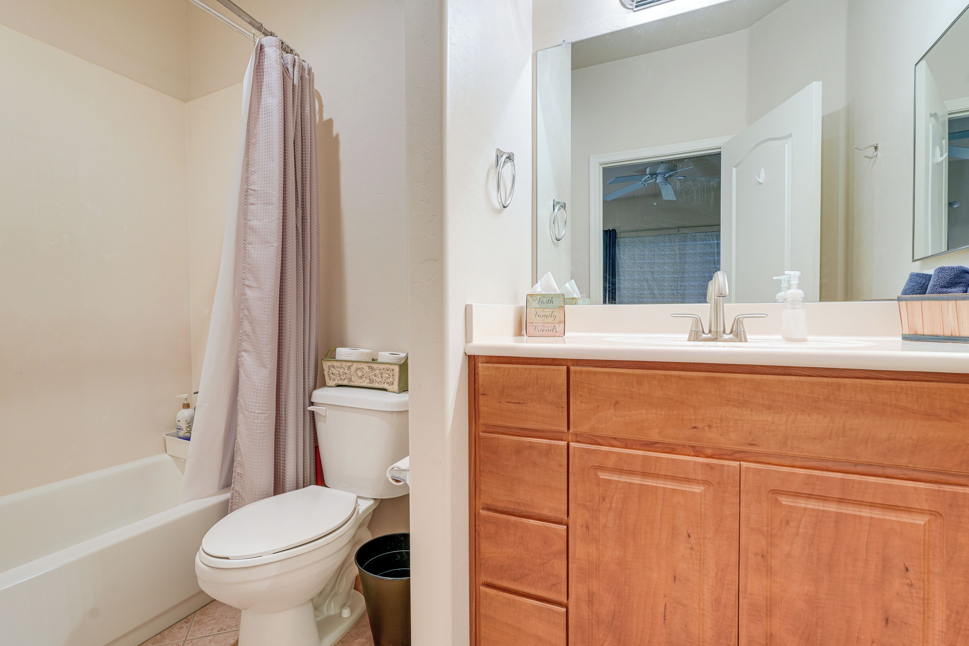 A bathroom with a white toilet, a wooden vanity, a mirror, and a shower curtain.