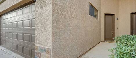 A residential building with a garage door, textured stucco walls, and a small window.