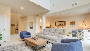 A spacious living room with a grey sofa, a blue armchair, and a wooden coffee table. - 1 Mi to Golf: Lake-view Condo w/ Pool in Chandler! (Chandler)