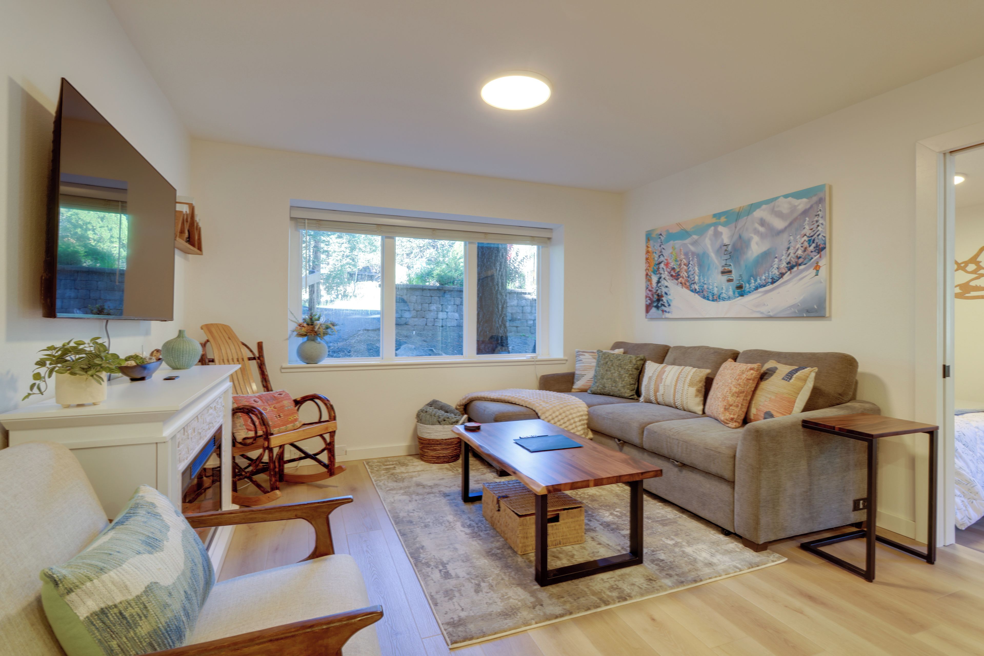A living room with a sofa, a coffee table, a TV, and a painting on the wall.