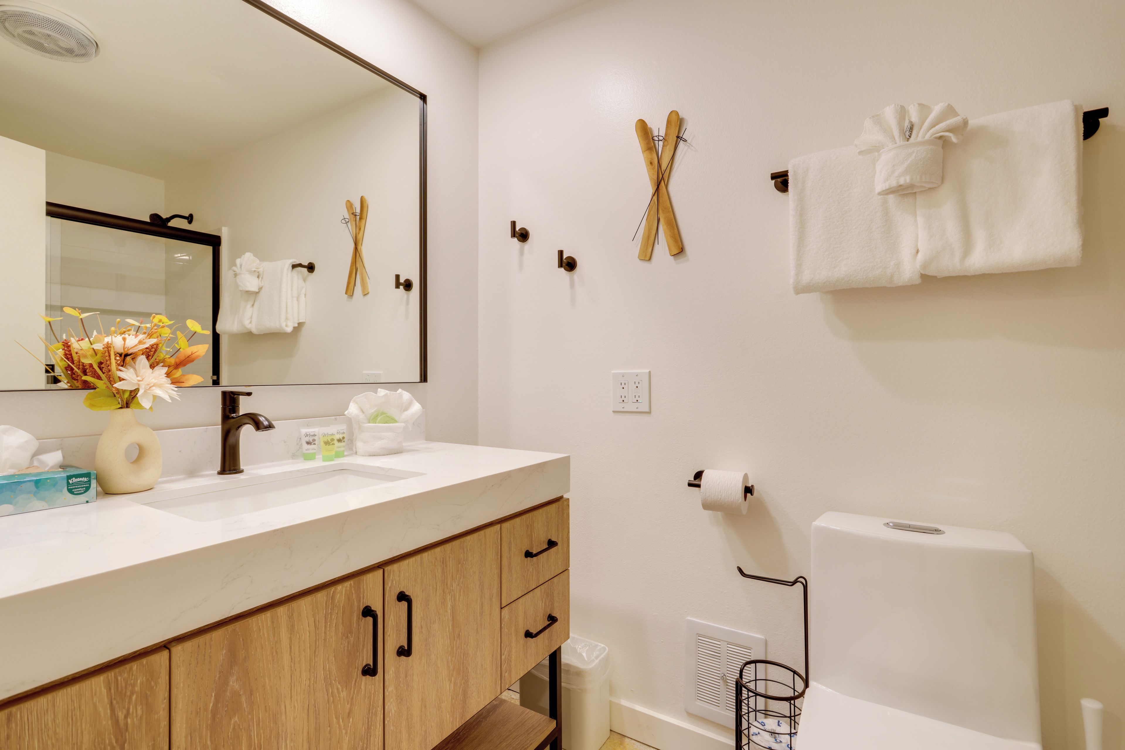 Une salle de bain avec un lavabo blanc, un miroir, un porte-serviettes et un support à papier toilette.