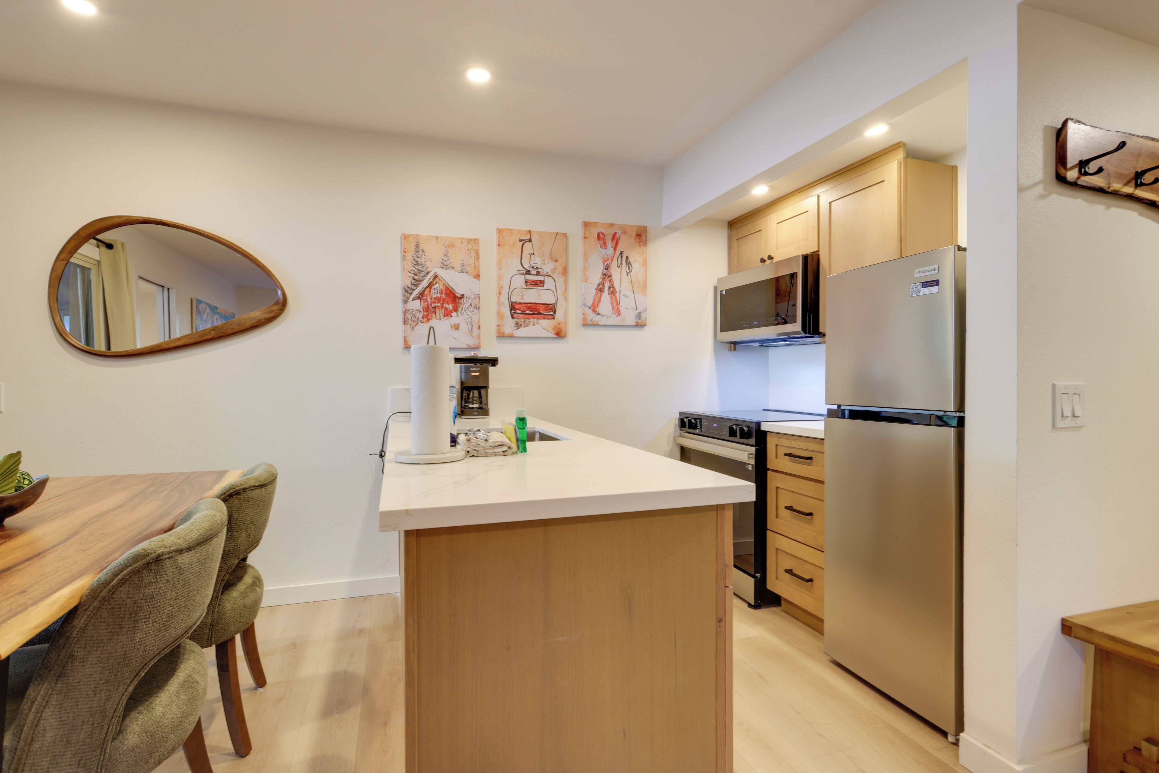 A modern kitchen with wooden cabinets, a stainless steel refrigerator, and a microwave.