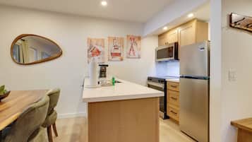 A modern kitchen with wooden cabinets, a stainless steel refrigerator, and a microwave.