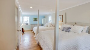 A bedroom with two beds, a wooden floor, and a window with curtains.