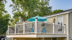A two-story house with a balcony deck, a staircase, and a covered outdoor seating area.