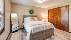 Un dormitorio con cama de madera, espejo, lámpara de pared y armario de madera.