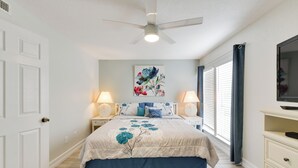 A bedroom with a bed, two bedside tables with lamps, a ceiling fan, a window with curtains, and a TV on a stand. - 3 Mi to Siesta Key Beach: Condo w/ Heated Pool! (Sarasota)