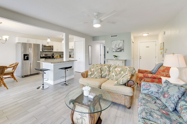 A spacious living area with a sofa, a coffee table, and a kitchen in the background. - 3 Mi to Siesta Key Beach: Condo w/ Heated Pool! (Sarasota)
