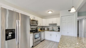A modern kitchen with stainless steel appliances, white cabinets, and a granite countertop. - 3 Mi to Siesta Key Beach: Condo w/ Heated Pool! (Sarasota)