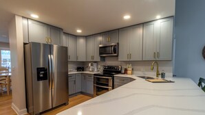 A modern kitchen with grey cabinets, stainless steel appliances, and a marble countertop.