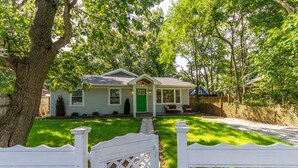 A single-story house with a green door, a front porch, and a white picket fence.