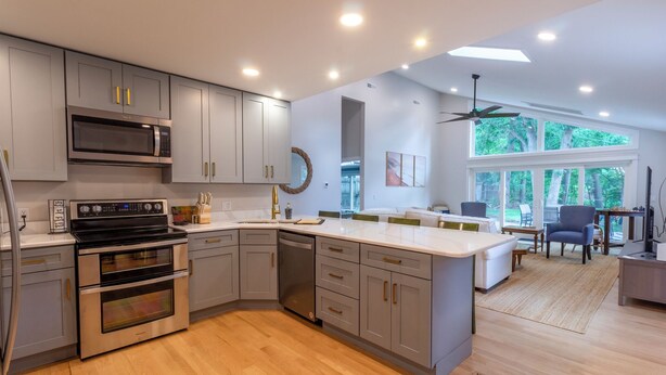 A modern kitchen with grey cabinets, stainless steel appliances, and a large island.