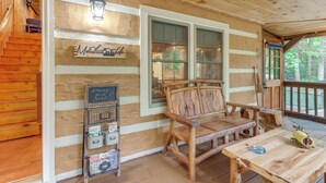 A wooden cabin interior with a wooden bench, a table, a lantern, and a sign that reads "Mountain Lodge." - Escape to the Mountains: Hot Tub Haven in Ellijay! (Ellijay)