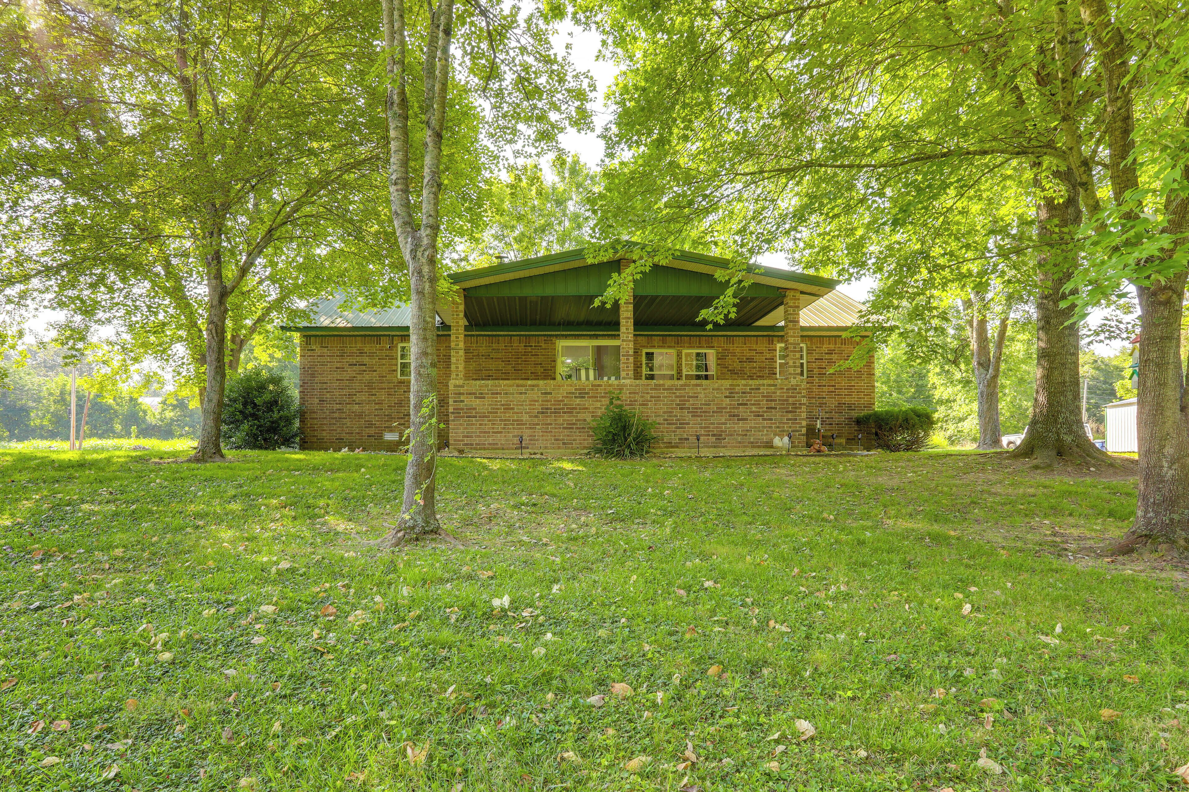 A brick building with a green roof, surrounded by trees and grass.