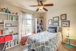 Un dormitorio con cama, estanterías, escritorio y ventilador de techo.
