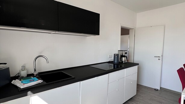 A modern kitchen with a black countertop, white cabinets, and a stainless steel sink.