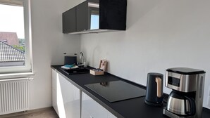 A modern kitchen with a black countertop, a coffee maker, and a kettle.