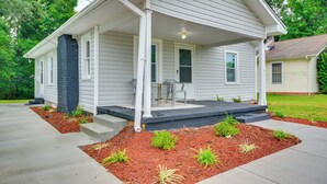 Ein einstöckiges Haus mit überdachter Veranda, Eingangstür und einer kleinen Terrasse.