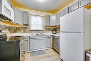 A modern kitchen with grey cabinets, a white refrigerator, and a built-in oven. - Home 1 Mi to Dtwn & High Point University! (High Point)