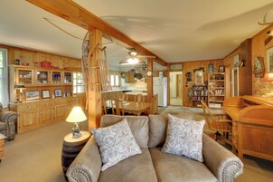 Uma sala de estar acolhedora com um sofá de couro marrom, armários de madeira e um espaço de jantar com mesa e cadeiras de madeira.